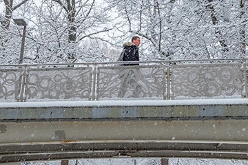 person walking on a snowy bridge